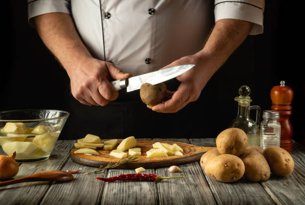 istock A skilled chef expertly peels and chops fresh potatoes in a rustic kitchen setting. The wooden table is adorned with various kitchen tools and ingredients, creating a warm and inviting atmosphere 2196423898