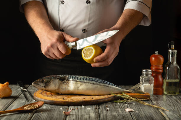 istock A skilled chef expertly slices a lemon above a whole mackerel on a wooden cutting board. Aromatic herbs and spices surround the fish, adding to the culinary charm of the cozy kitchen atmosphere 2196423954