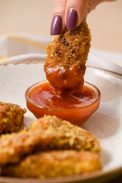 istock Hand Dipping Crispy Nugget into tomato sauce. 2196424152