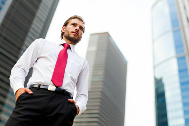 istock Businessman standing with hands in pockets looking up at skyscrapers 2196424164