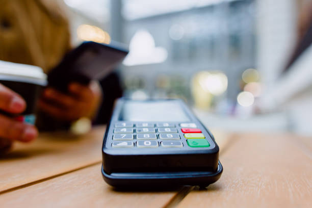 istock Customer paying using contactless smartphone nfc technology at pos terminal, coffee shop blurry mall interior visible behind payment process 2196429047