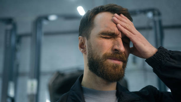 Close up Caucasian ill sick unwell man mechanic technical engineer automotive industry worker working hard at auto car truck service suffer headache feeling bad migraine overworked painful head ache