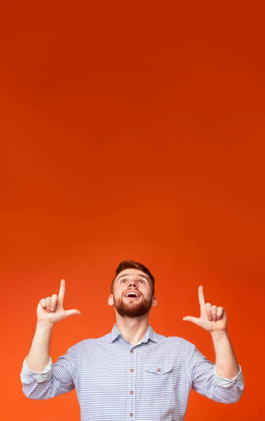 istock Man Expressing Joy With Hands Raised Against an Orange Background During a Casual Moment 2196431549