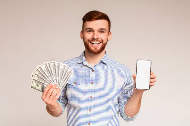 istock Handsome guy with cellphone and fan of dollars 2196431563