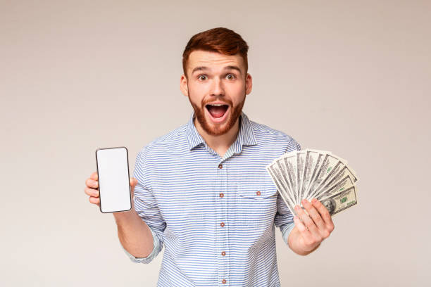 istock Surprised millennial guy with money and cellphone 2196431575