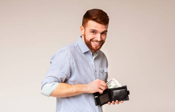istock Handsome man showing black wallet with dollars and smiling 2196431597