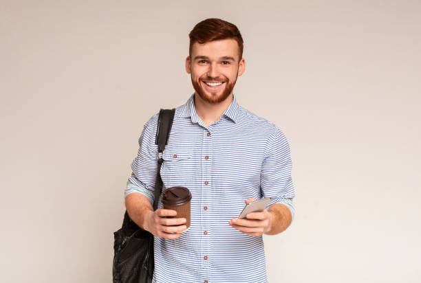 istock Cheerful man holding cup of coffee and using phone 2196431604