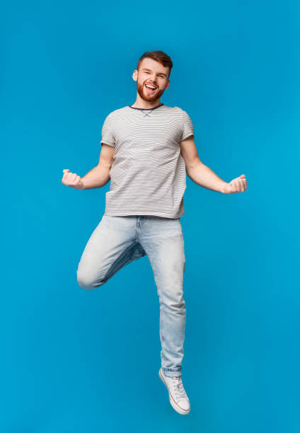 istock Satisfied caucasian man jumping on blue background 2196431674