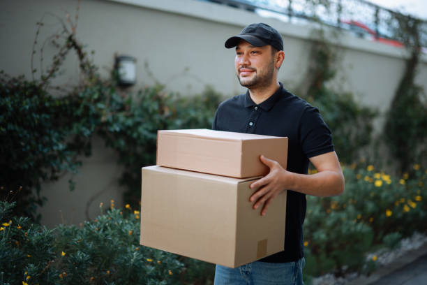 istock Delivery man holding pile of cardboard boxes in front 2196437228
