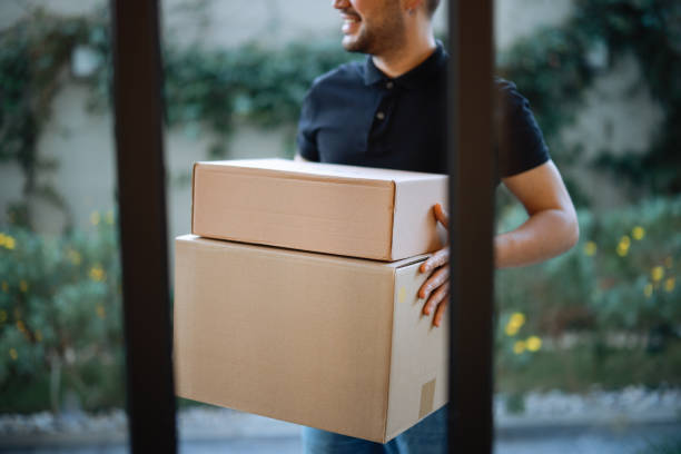 istock Delivery man holding pile of cardboard boxes in front 2196437635