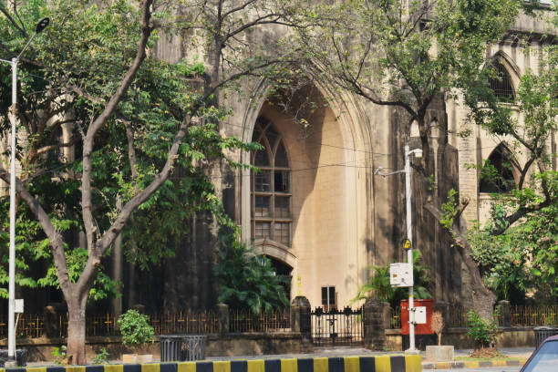 A gothic-style church stands amidst greenery in an urban setting, showcasing beautiful architecture and a serene atmosphere in the surrounding area.