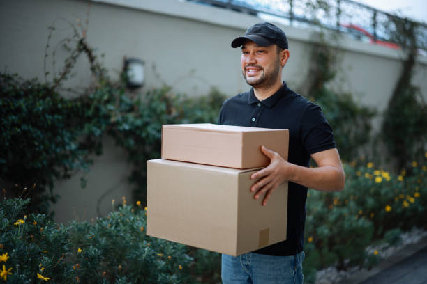 istock Delivery man holding pile of cardboard boxes in front 2196438369