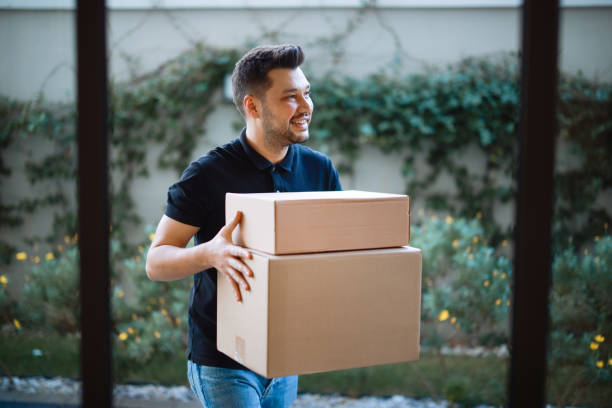 istock Delivery man holding pile of cardboard boxes in front 2196438507