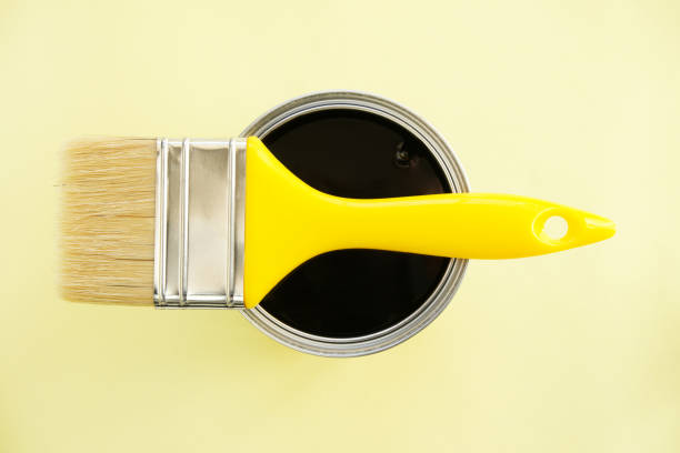 istock Paint brush with black paint on yellow background 2196438928