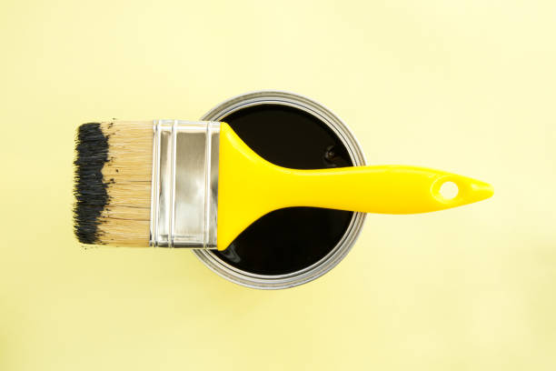 istock Paint brush with black paint on yellow background 2196438934