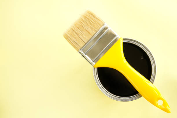istock Paint brush with black paint on yellow background 2196438951