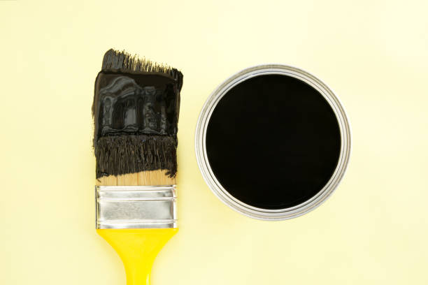 istock Paint brush with black paint on yellow background 2196438990