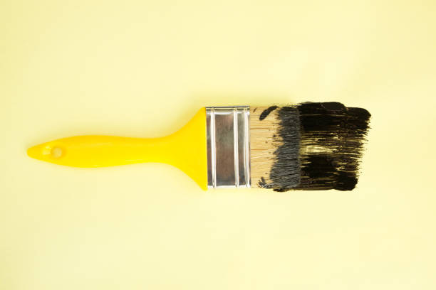 istock Paint brush with black paint on yellow background 2196439013