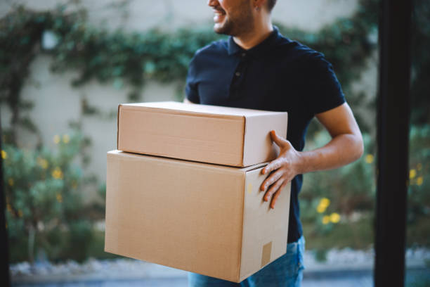 istock Delivery man holding pile of cardboard boxes in front 2196439558