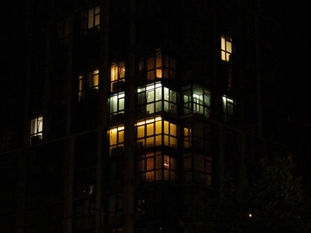 istock Glowing windows of the multi-storey building in night 2196440417