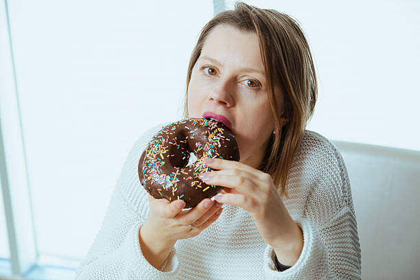 istock Woman with hunger eating chocolate glazed donut, dieting theme. 2196441214