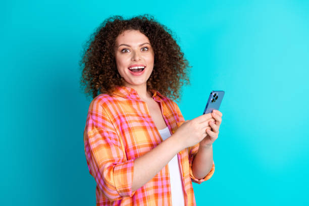 istock Young woman holding smartphone with a surprised expression against a turquoise background 2196441340