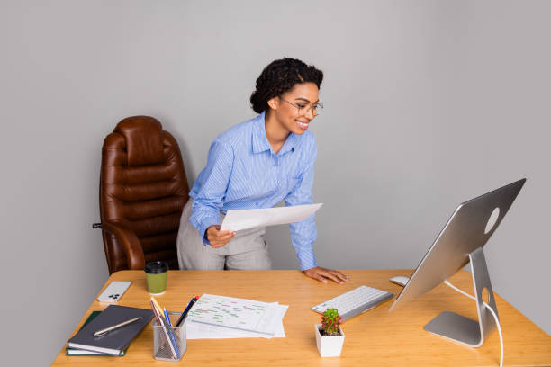 istock Professional young woman reviewing documents at her office desk with a computer and reading glasses, exuding confidence and focus. 2196441809