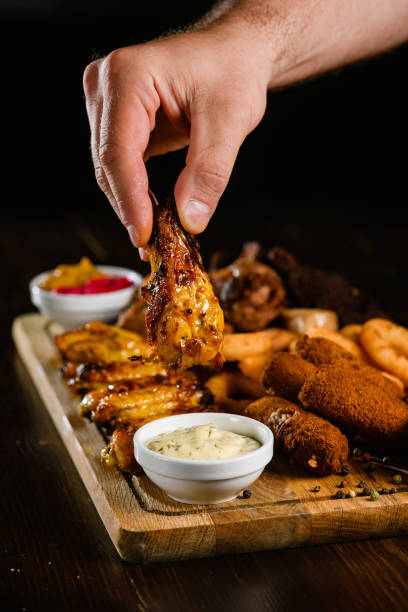 Hand Holding a Crispy Chicken Wing with Sauce