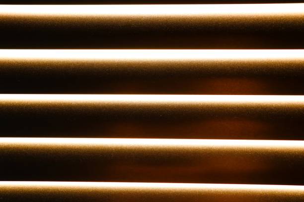 A closeup of wooden blinds illuminated by warm light, creating an elegant and inviting ambiance in the room