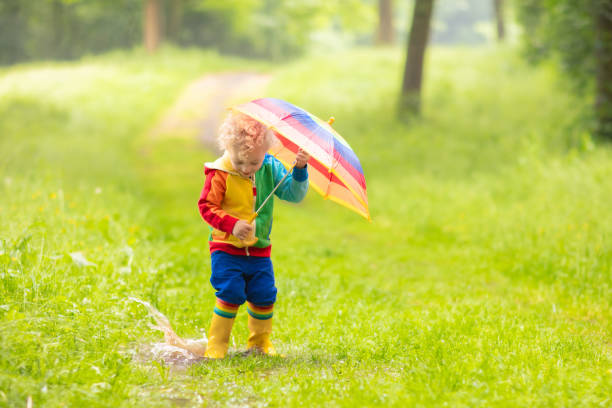 istock Child playing in the rain under umbrella 2196447919