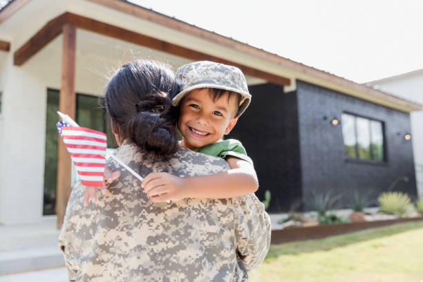 istock Soldier Mom Hugging Son, Holding American Flag, Home 2196449315