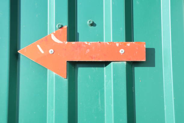 istock A vivid orange arrow sign indicating a left direction against a bright green background 2196452635
