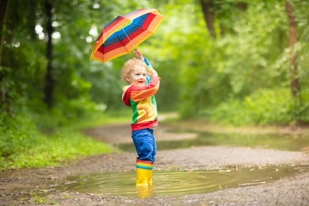 istock Child playing in the rain under umbrella 2196453563
