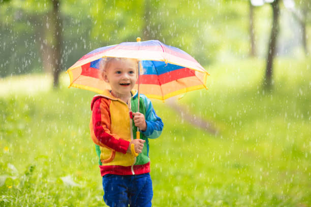 istock Child playing in the rain under umbrella 2196453573