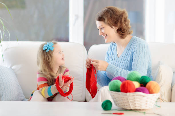 istock Mother and daughter knitting woolen scarf 2196453655