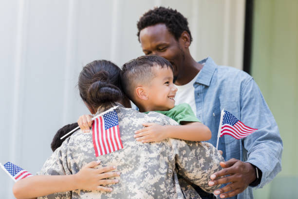 istock Military homecoming: Family embraces soldier with American flags 2196455492