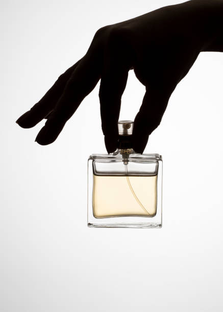 istock Hands elegantly hold a transparent perfume bottle, the golden fluid inside catching the light, all set against a white background. 2196458502