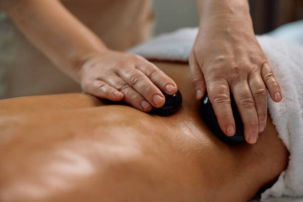 istock Close up of spa therapist using hot stones during back massage. 2196459611