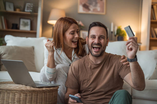 istock Couple celebrating a successful purchase after online shopping 2196465484