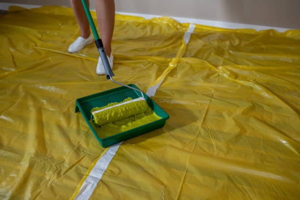 Paintbrush and roller, with yellow paint.