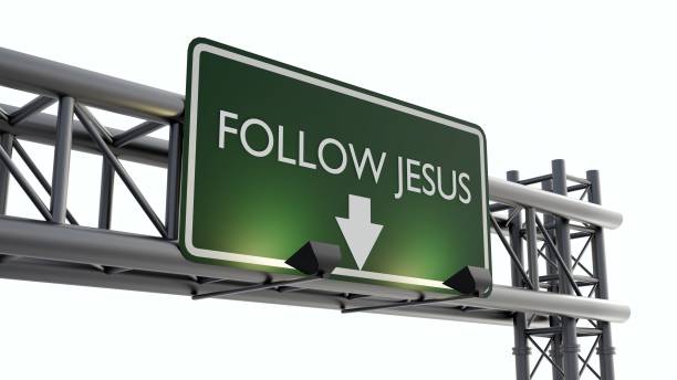 a highway sign featuring 'FOLLOW JESUS' in white text