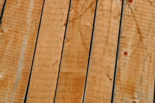 The image features a detailed perspective of wooden planks arranged diagonally, highlighting their natural textures and warm colors under soft daylight.