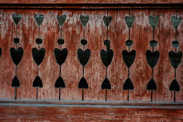The detailed wooden panel showcases heart-shaped cutouts, revealing a contrasting dark background and displaying weathered craftsmanship.