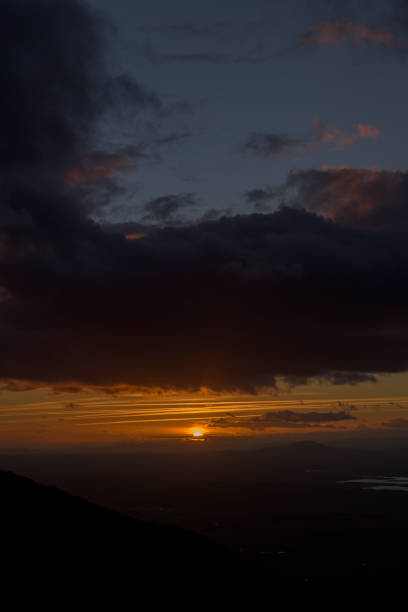istock Sun hiding on the horizon with reddish and orange tones at sunset vertically 2196474464