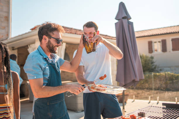 istock Hispanic Male Grilling BBQ and Toasting by the Pool 2196483168
