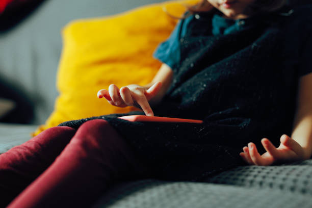 istock Little Child Playing on a Smartphone Sitting on a Couch 2196486237