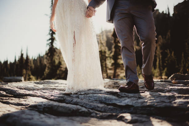istock Bride and groom holding hands walking in the mountains 2196487196