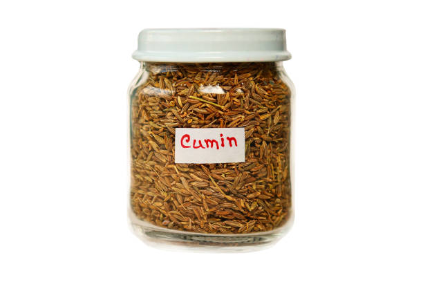 Cumin in a glass jar isolated on a white background.