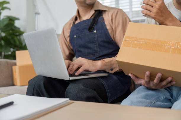 istock Delivery professional typing on a laptop while another holds a package in a collaborative workspace 2196488217