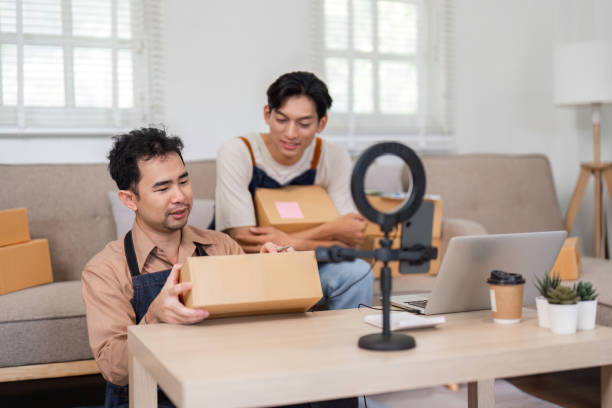 istock Entrepreneurs preparing packages for unboxing while filming in their home office 2196488376